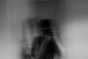 A horizontal black and white image of me reflected in a mirror. The entire image is blurred from moving whilst pressing the shutter button.